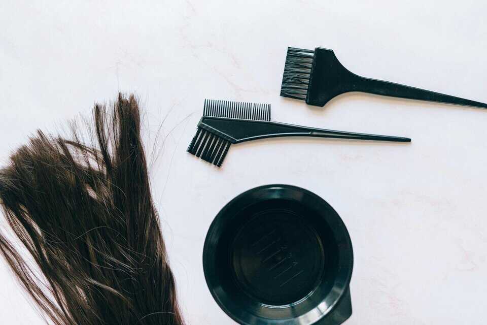 Zwei Haarfärbepinsel mit einer schwarzen Schale und einer brünetten Haarsträhne